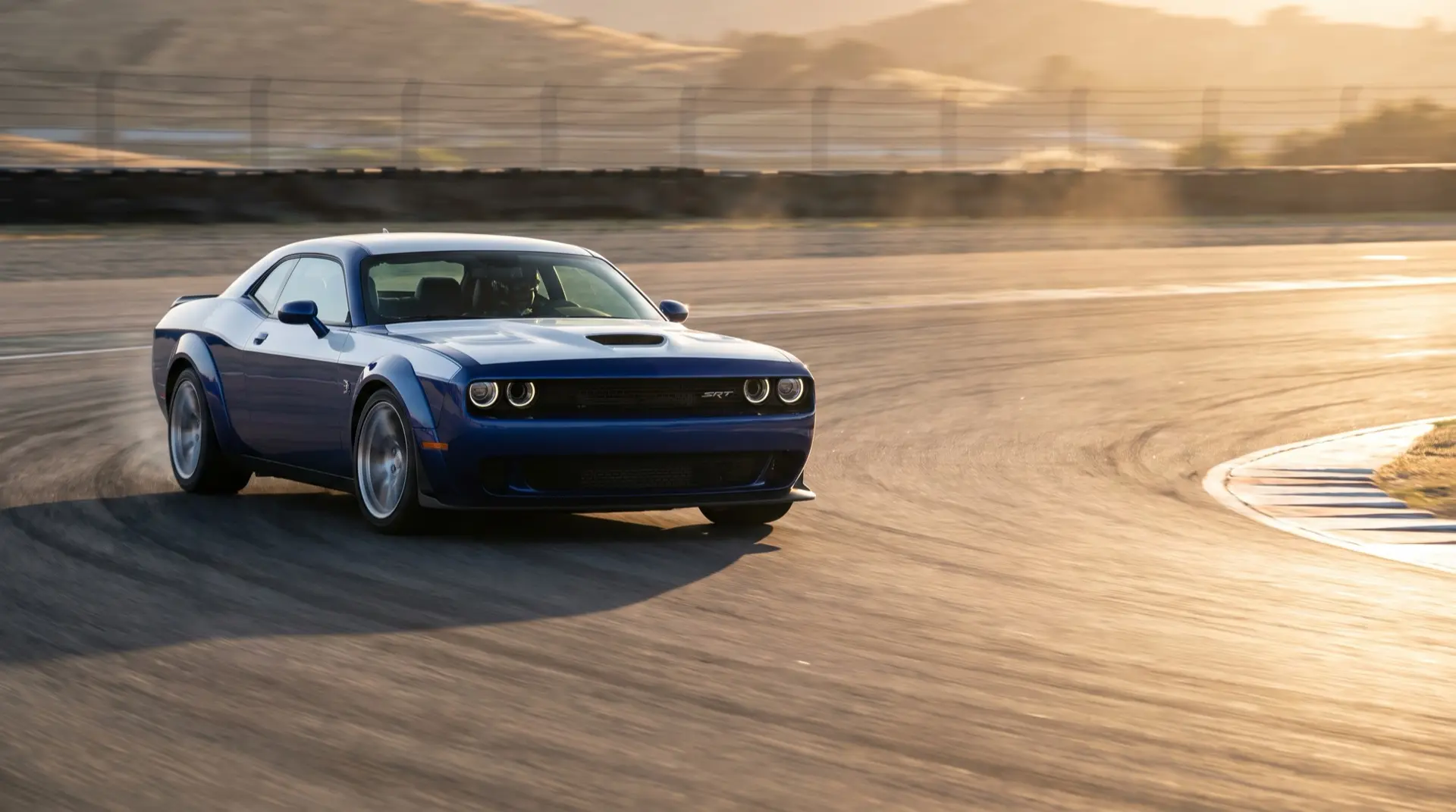 Blue widebody Dodge Challenger SRT cornering on a race track